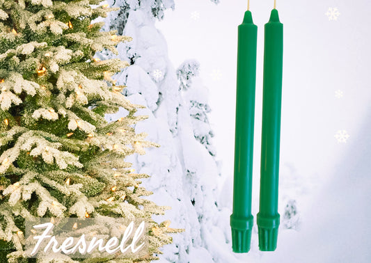Festive green beeswax colonial style candlesticks on a festive winter background of an evergreen tree with snow.
