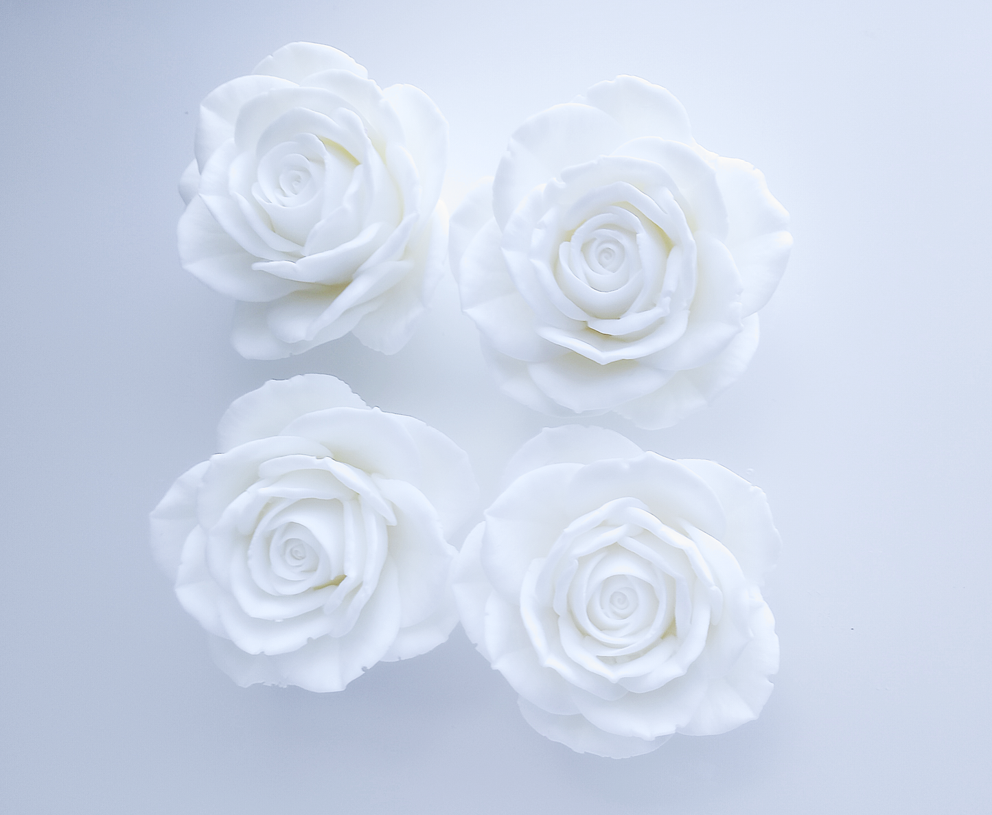 A collection of four handcrafted white rose soap flowers arranged together, highlighting the elegant floral design and artisan quality.