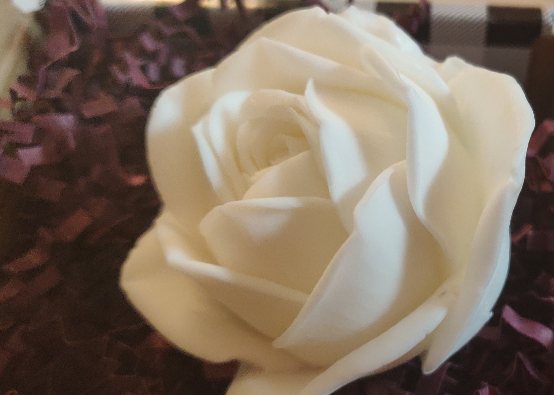 Close-up of a hand-poured white rose soap showing intricate petal details.